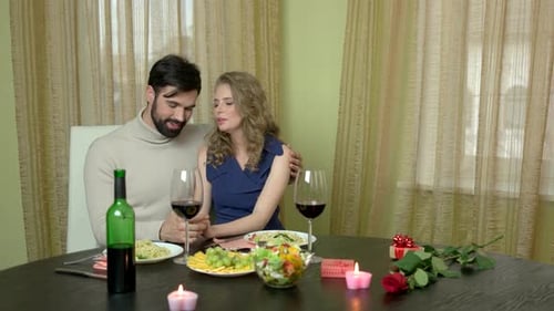 Romantic Couple Embracing at Candlelit Dinner Table