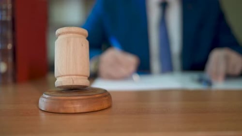Wooden Gavel in Front of Person Writing
