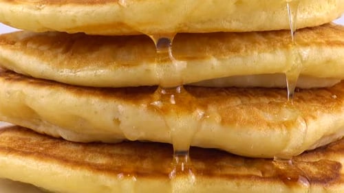 Pancakes with honey on a white background.