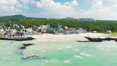 People enjoying summer vacation and wavy beach scenery. Jeju Island.