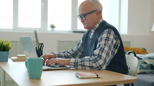 Senior Man Using Laptop at Desk Indoors