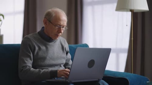 Senior Man Typing on Laptop at Home