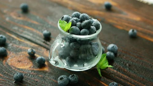 Fresh Blueberries in Glass Pitcher on Wooden Surface