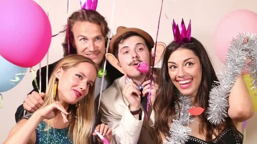 Group of young friends having a great time in party photo booth