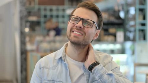 Man Massaging Stiff Neck in Office Setting