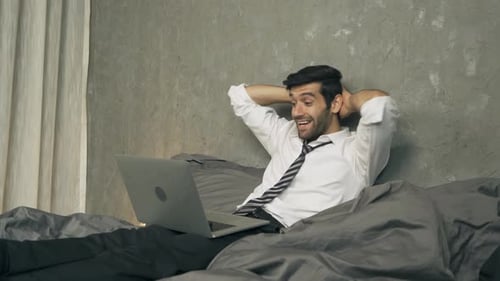 Excited Man Working on Laptop in Bed