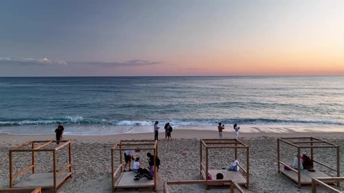 People sit on the beach and watch the sunset