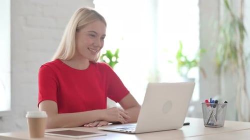 Young Blonde Woman Talking on Video Call on Laptop in Office