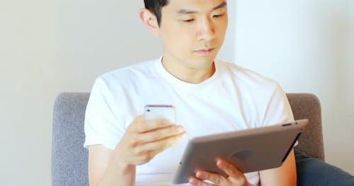 Man with Tablet and Phone on Couch