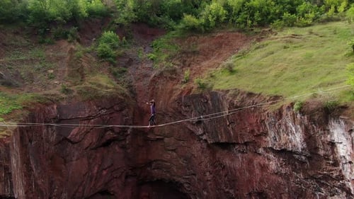 High Angle View on a Man Walking the Tightrope Over the Scary Pit