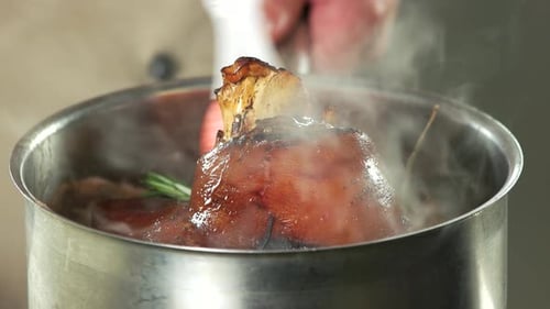 Chef Basting Delicious Pork Knuckle in Kitchen