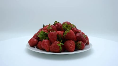 Strawberries on a plate rotating on a white background. Strawberry ripe season