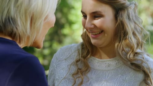 Smiling Bride Holding Bouquet with Friend Outdoors
