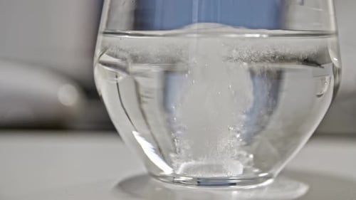 Brausetabletten in extrem Zeitlupe ins Wasser fallen lassen, Bürohintergrund