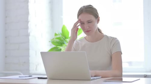Woman with Headache Rubbing Temples at Desk