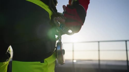 Closeup de um alpinista industrial prendendo um mosquetão com um jumper em um arnês
