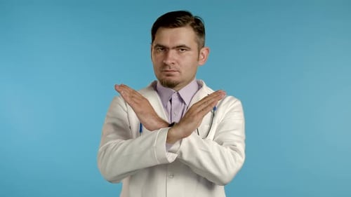 Portrait of Serious Doctor in Professional Medical White Coat Showing No, Stop Crossing Hands Sign