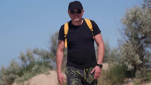 Man Hiking on Beach with Dunes on Sunny Day