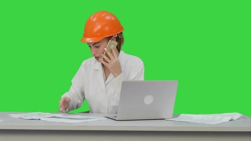 Mujer en casco naranja llamando al teléfono discutiendo el plan de restricción en una pantalla verde, Chroma Key
