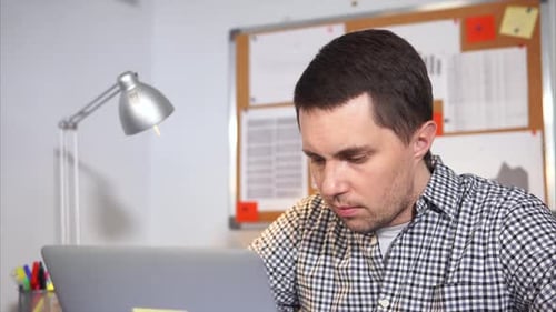 Young Man Office Worker Typing at Notebook and Thinking.