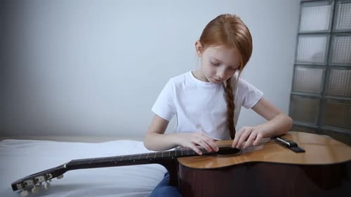 Une jolie blogueuse adolescente avec une guitare à la main parle à la caméra et raconte comment elle a appris à