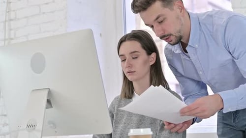 Coworkers Reviewing Paperwork by Computer