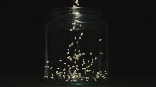 Grains Being Poured Into Clear Glass Jar