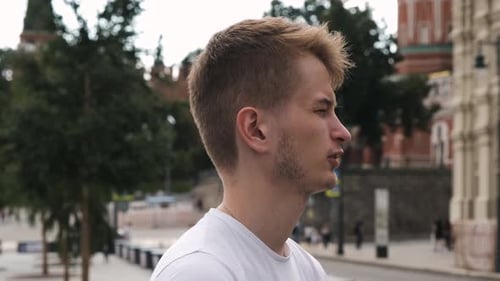 Young Guy with Short Blond Hair in White T-shirt Talking To Someone We Can Not See. Handsome Man Is