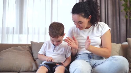 Mother and Child Using Tablet on Sofa