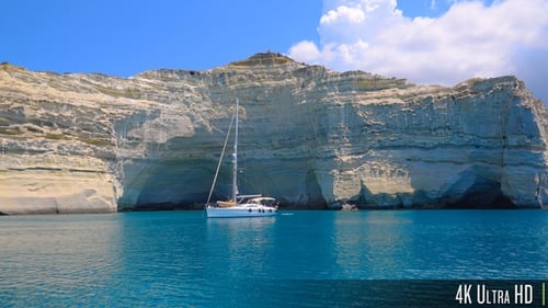 4K Dramatisch Klippen und kristallklares Wasser auf der griechischen Insel Milos mit vor Anker liegenden Segelbooten