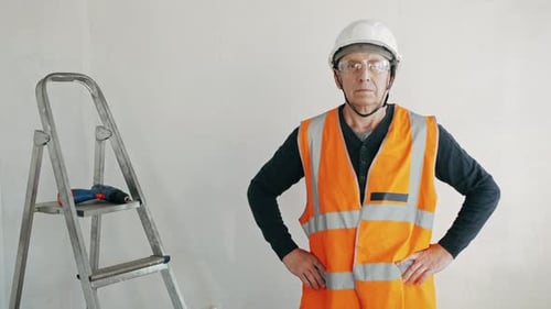 Man in Safety Gear Stands by Ladder
