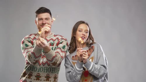 Couple Celebrating with Sparklers Wearing Christmas Sweaters