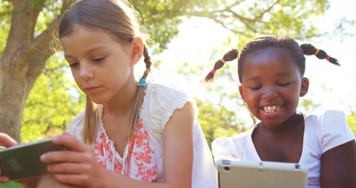 Girls Using Tablets Together in Sunny Park