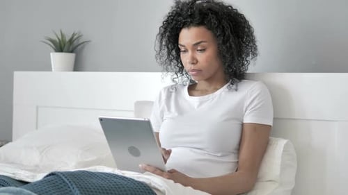 Young Adult Using Tablet in Bed