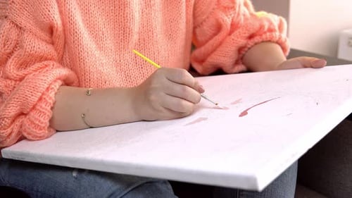 Young Adult Painting a Canvas with a Paintbrush