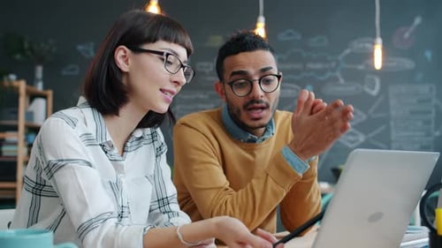 Male and Female Coworkers Discussing Business Ideas in Open Space Office Using Laptop