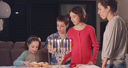 Family Celebrates Hanukkah with Lit Menorah and Donuts
