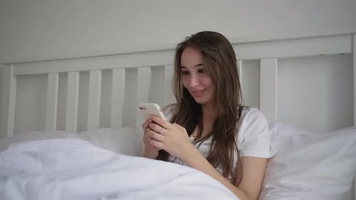 Woman Using Cell Phone in Bed