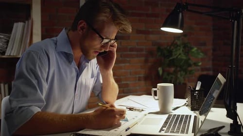 Focused Young Adult Architect Works Late at Desk