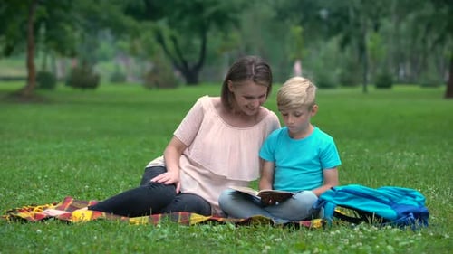 Woman and Child Reading Book Together in Park