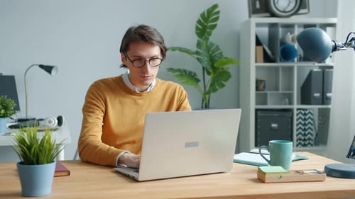 Cheerful Guy Using Laptop Typing Working at Table in Office Concentrated on Job