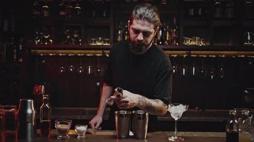 Un barman expérimenté verse du liquide à l'aide d'un doseur dans un shaker