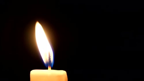 Nahaufnahme einer Kerzenflamme auf schwarzem Hintergrund. Schleife.