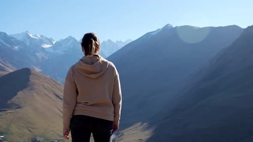 Brunette Woman Approaches the Edge of a Rock and Spreads Her Arms to the Sides Against