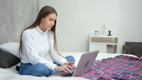 Woman Typing on Laptop While Sitting on Bed