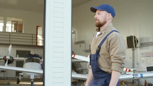 Técnico de mantenimiento masculino caminando por hangar