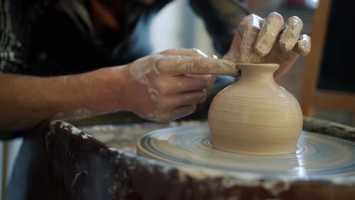 Close-up of Potter's Hands Covered with Clay Making Beautiful Vase on Throwing Wheel