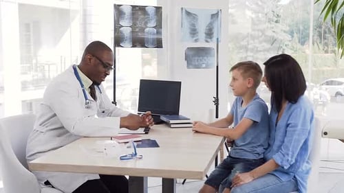 African Young Doctor Giving Prescription to Cute Mother with Here Son at Clinic