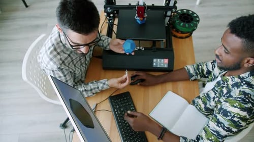 Cheerful Engineers Manufacturing 3D Printed Detail Using Computer Talking in Office