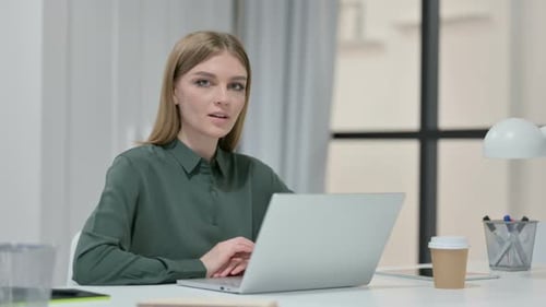 Smiling Woman Working on Laptop at Desk